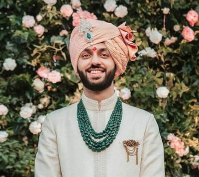 A man standing in wedding attire with the groom mala