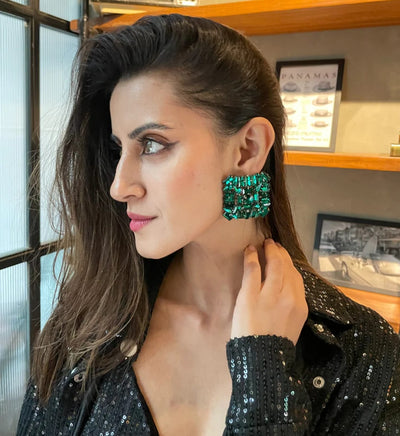 A lady wearning oversized zirconia studs in green color