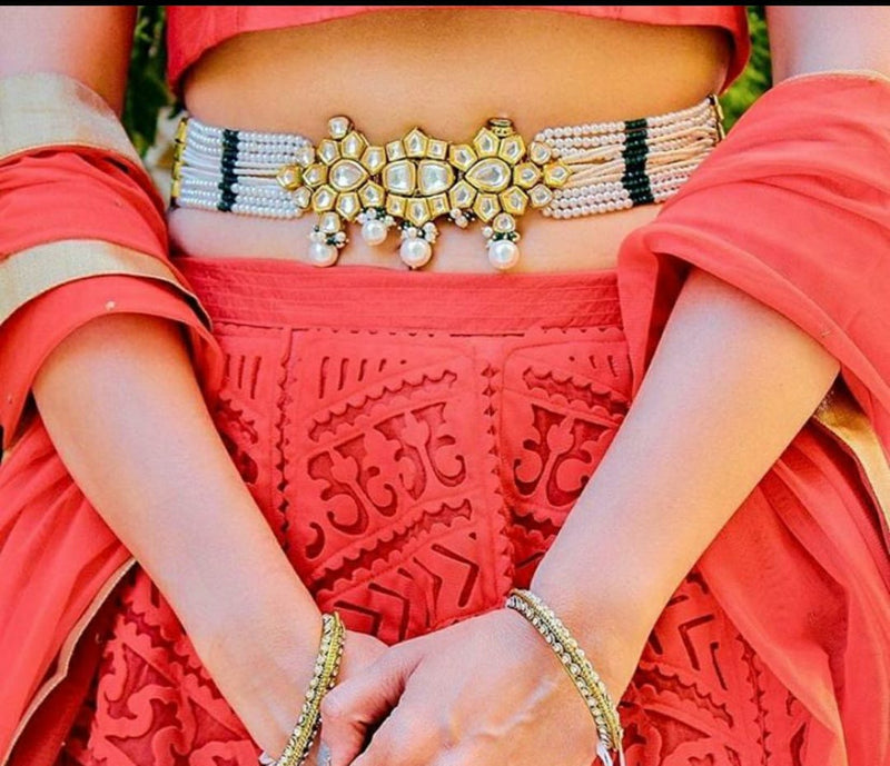 A lady shows a Kasturi pearl waist belt with a Kundan brooch on her waist