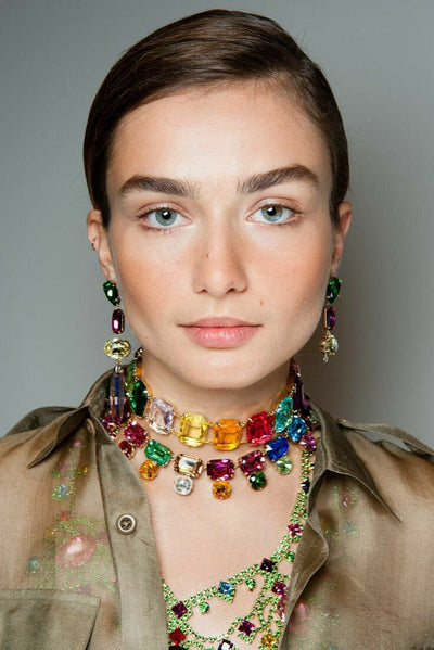 A lady wearing a two layer multicolor crystal choker necklace set and earrings