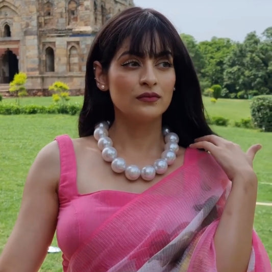 A woman is wearing a big pearl necklace 25mm on the neck.