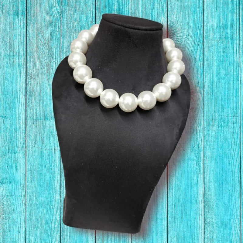 A big pearl necklace is on the neck display.
