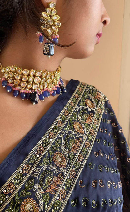 A lady is wearing blue beaded choker necklace with earrings